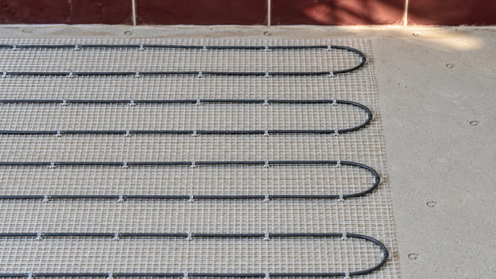 Close detail of electric heating cable fixed to mesh before the bathroom floor finish is installed.
