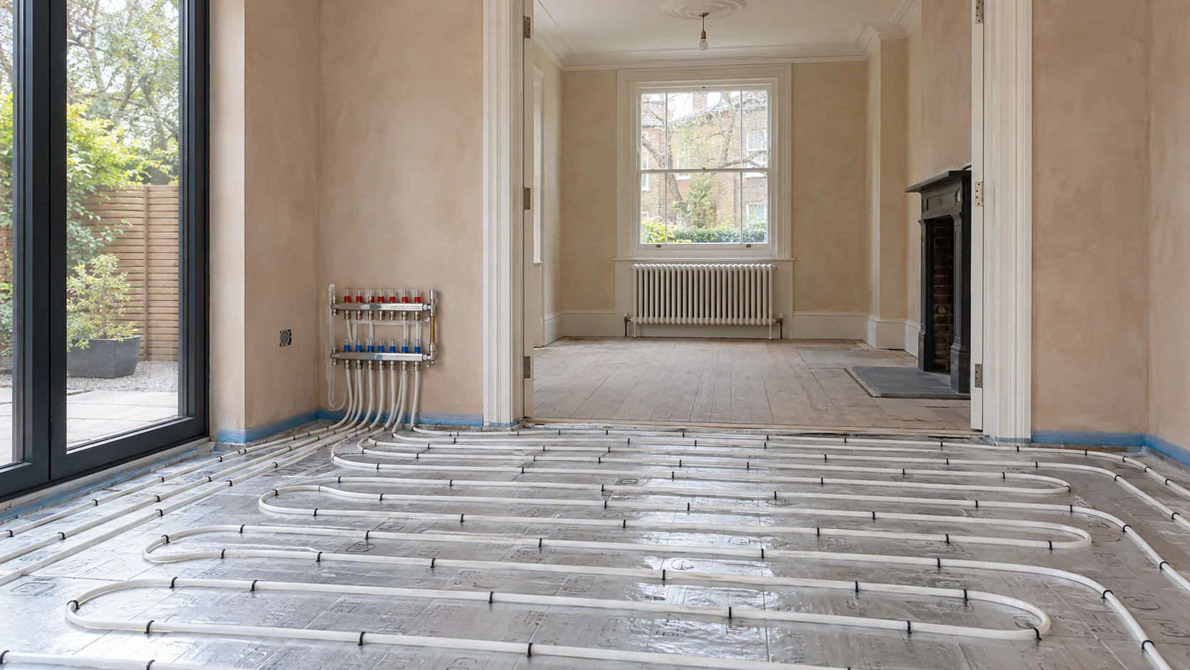 Radiator and white underfloor heating pipe loops during a domestic heating refurbishment.